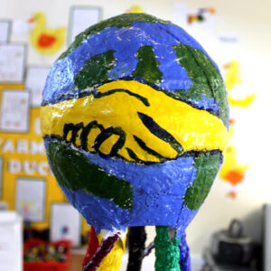 The balloon formed globe on top of the sculpture and the shaking hands school symbol