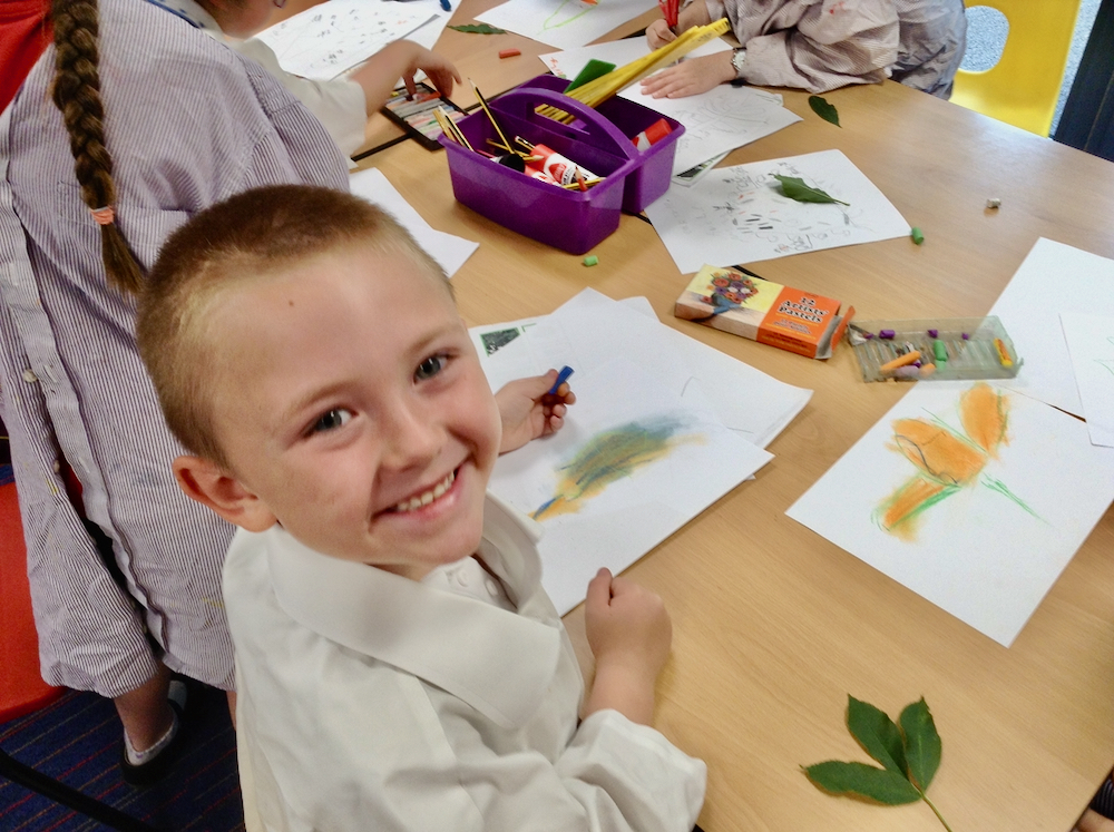 Year One boy at Hauxton Primary School drawing leaves with pastels with Pamela Stewart for Inspire 