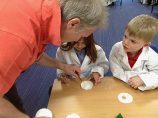 Professor John Love helps children place seeds in petri dishes for a science experiment at Hauxton Primary School