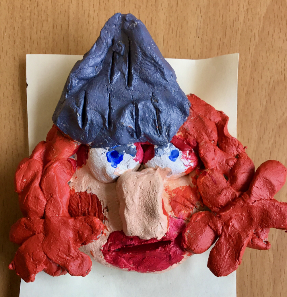 A clay Viking made in clay and painted with orange, curly hair, a large, pink nose, blue eyes and metallic, grey helmet, made by a year four pupil taught by art teacher Sue Brown