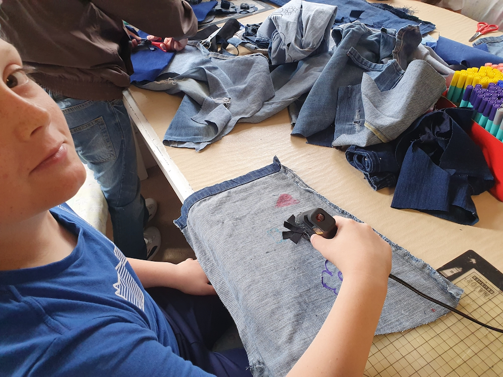 Boy working with a glue gun on discarded jeans part of Inspire project with teacher Natalie Bailey in collaboration with AccessArt and the Fitzwilliam Museum, Cambridge