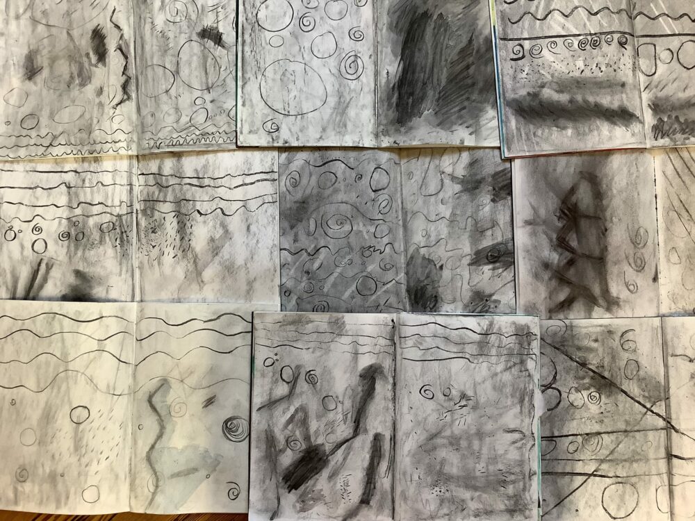 A collection of charcoal warm ups on the wall.