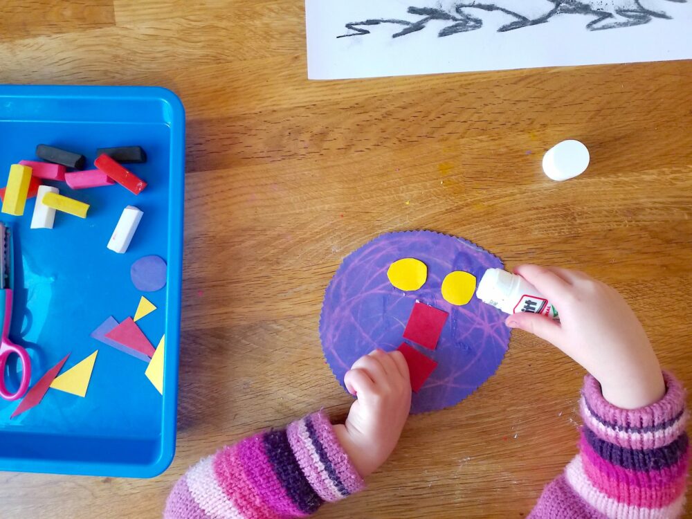 Glueing shapes onto a circle of paper.